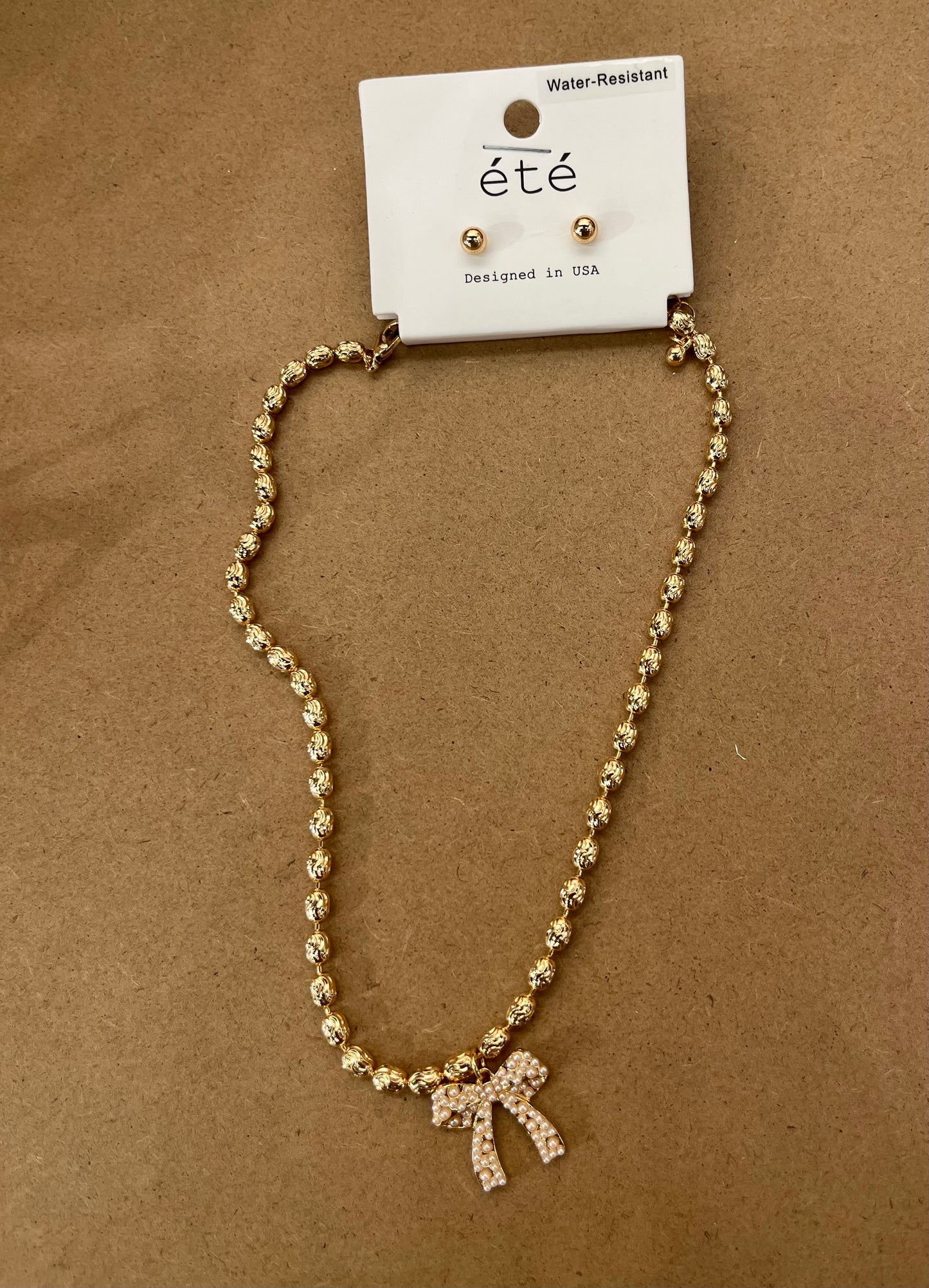 Gold necklace with pearl bow with gold stud earrings